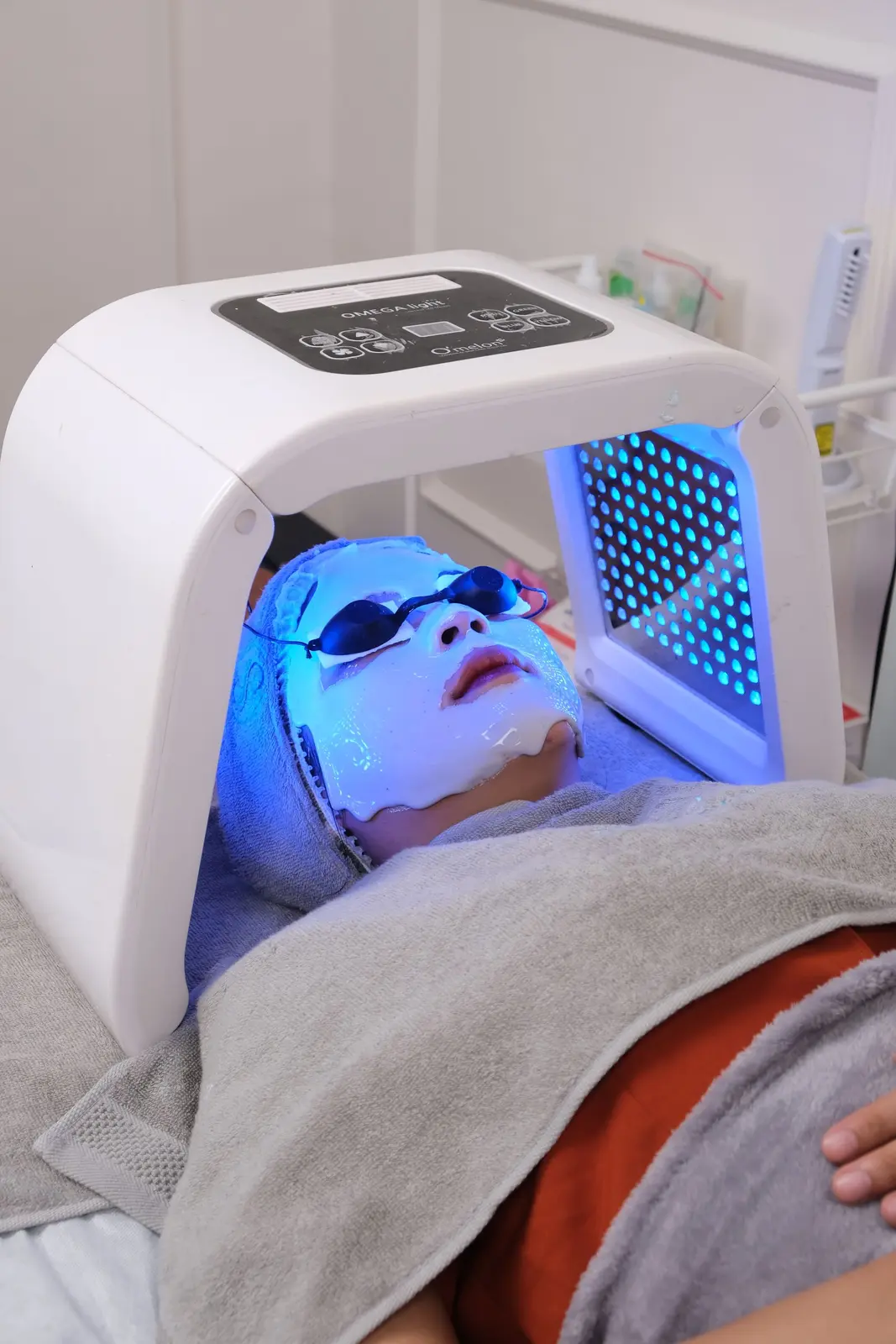 Cliente sous un panneau LED à lumière bleue lors d'un soin du visage