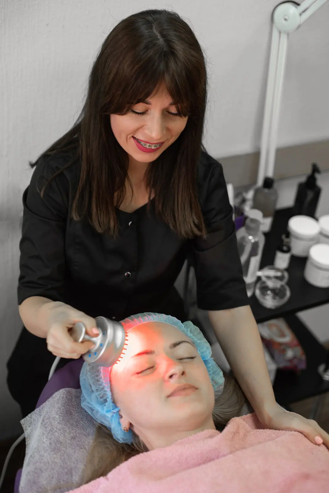 Esthéticienne réalisant un soin de photobiomodulation sur le visage d'une cliente