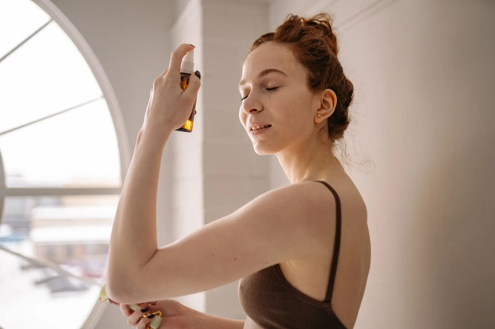 Femme recevant une brume hydratante sur le visage, ambiance douce et lumineuse