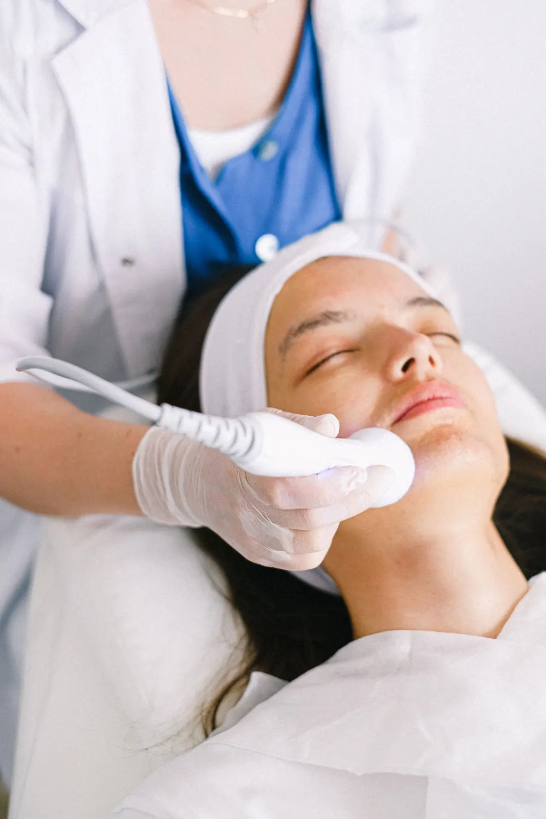 Esthéticienne appliquant une pièce à main à ultrasons sur le visage d'une cliente
