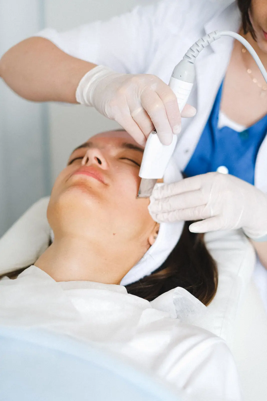 Esthéticienne passant une sonde à ultrasons sur le visage d'une cliente